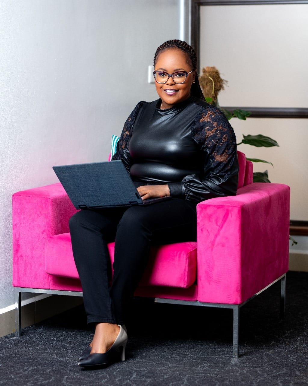 Mary Chege smiling while seated on a sofa at an office.